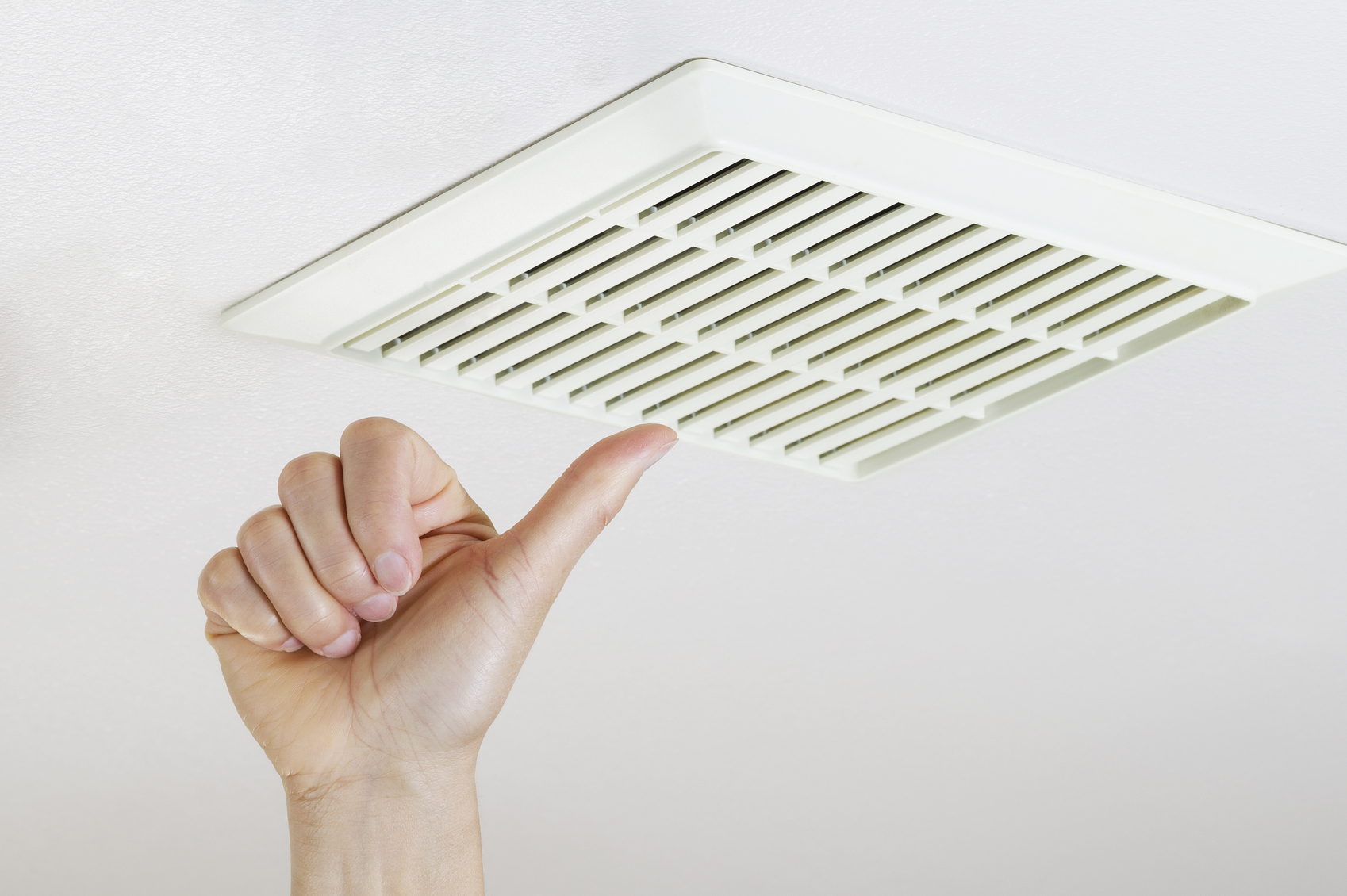 Close up horizontal photo of female hand giving thumbs up after cleaning and installing bathroom fan vent cover from ceiling